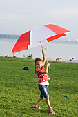 Girl (4-5 years) carrying sunshade, Lake Ammersee, Upper Bavaria, Bavaria, Germany