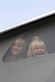 Two children (3-4 years) looking out of a motorhome