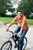 Middle aged man riding a bicycle over grass, Bavaria, Germany