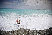 Girl and boy playing in the sea, Nice beach, Cote d'Azur, Provence, France