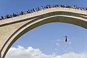 Tourists watch a man diving from the The new Old Bridge into the river Neretva Mostar Bosnia and Herzogovina