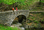 Paar mittleren Alters sitzt auf Steinbrücke, Tessin, Schweiz