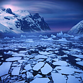 Ice floes near the Antarctic Circle with lenticularis cloud over mountain peak, Antarctic Peninsula, Antarctica