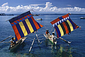 Menschen fahren auf Ausleger Booten mit bunten Segeln, Zamboanga, Mindanao, Philippinen, Asien