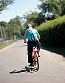 Man on bicycle in the summer heat, near boat harbour in Burg-Kauper, Upper Spreewald, biosphere reservat, Spreewald, Brandenburg, Germany