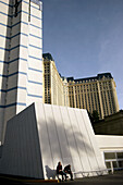 Visitors resting under the building of Bally’s Hotel and Casino with Paris Hotel and Casino in the background, Las Vegas, Nevada, USA