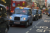 Taxi Cabs, double decker buses and cars on Oxford Street, London, England, at twilight.
