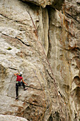 Female climber reaching the top of a route in the City of Rocks, Idaho, USA.
