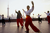 People dance on the Bund or Wai Tan. The waterfront of Shanghai. Across the river is the Pudong skyline. China