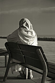 Muslim woman sitting in front of the sea.