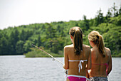 girl 13 with girl 18 fishing together on dock at cottage