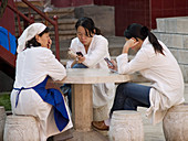 workers on a break play with their cell phones, Kunming, China