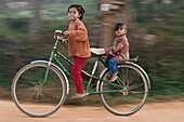 boy and girl on the bicycle in the village along the Tonle Sap Cambodia
