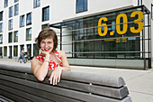 Junge Frau sitzt auf einer Bank, Köln, Nordrhein-Westfalen, Deutschland