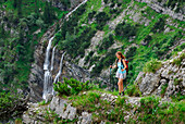 young woman hiking in front of waterfall, Soiern range, Karwendel range, Upper Bavaria, Bavaria, Germany