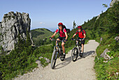 Couple mountainbiking, Kampenwand, Chiemgau range, Chiemgau, Bavaria, Germany