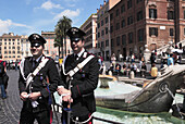Two Carabinieri at Fontana della Barcaccia on Piazza di Spagna, Spanish Steps in background, Rome, Italy