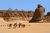 Tourists riding camels through the desert. Akakus mountain. Fezzan region. Sahara desert. Libia.
