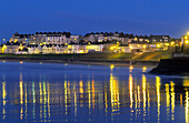 Blick auf beleuchtete Häuser an der Küste am Abend, Portrush, County Antrim, Irland, Europa