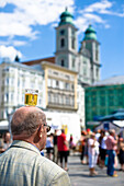 Man balancing a beer mug on his head, dome in the background, Central Square, Linz, Upper Austria, Austria