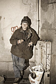 Ein Obdachloser mit Plastiktüte steht vor einer Wand, Linz, Oberösterreich, Österreich