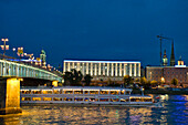 Ein Ausflugsschiff fährt nachts auf der Donau, Kunstuniversität im Hintergrund, Linz, Oberösterreich, Österreich