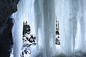 View through frozen waterfall to a group of ice climbers, Immenstadt, Bavaria, Germany