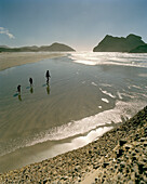 Mother with children on the beach at lowtide, Wharariki Beach, northwest coast, South Island, New Zealand