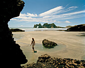 Woman walking through tidal pools at lowtide at Wharariki Beach, northwest coast, South Island, New Zealand