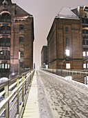 Schneebedeckte Brücke und Gebäude in der Speicherstadt, Hamburg, Deutschland