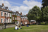 Leute sitzen im Gras an der Cathedral Close, Exeter, Devon, England, Großbritannien