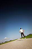 Jogger standing on road, Munsing, Bavaria, Germany