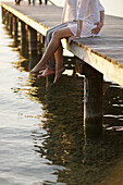 Couple sitting on a jetty, Ambach, Lake Starnberg, Bavaria, Germany