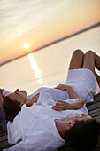 Couple lying on a jetty, Ambach, Lake Starnberg, Bavaria, Germany