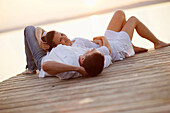 Couple lying on a jetty, Ambach, Lake Starnberg, Bavaria, Germany