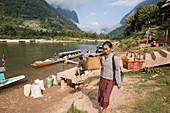 Eine Frau trägt Körbe am Ufer des Flusses Nam Ou, Provinz Luang Prabang, Laos