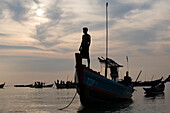Man standing on a fishing boat in the sunset in Ngapali Beach, Gulf of Bengal, Rakhine State, Myanmar, Burma