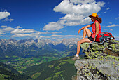 Junge Frau auf Felsen sitzend mit Steinernem Meer und Hochkönig in den Berchtesgadener Alpen im Hintergrund, Hundstein, Salzburger Schieferalpen, Salzburg, Österreich