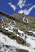 Frau auf einer Brücke über einen Bach, Nationalpark Hohe Tauern, Salzburg, Österreich