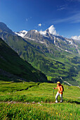 junge Frau auf Wanderweg durch Blumenwiese, Aufstieg zur Pfandlscharte, hinten Wiesbachhorn, Hohe Tauern, Nationalpark Hohe Tauern, Salzburg, Österreich
