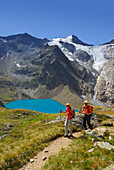 couple hiking above lake Gruenausee, Wilder Freiger and galcier Wiilder-Freiger-Ferner in background, Stubaier Alpen range, Stubai, Tyrol, Austria