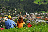 Paar sitzt in einer Wiese und blickt auf Brixen, Eisacktal, Trentino-Südtirol, Italien