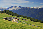 Blick über Almhütten auf die Dolomiten mit Geislergruppe und Sella, Südtirol, Italien