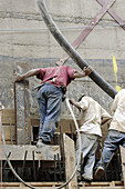 Construction workers pouring wall holding cement/concrete hose