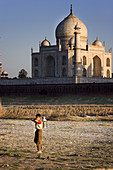 Boy with milk pot and Taj Mahal in background, Agra. Uttar Pradesh, India