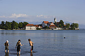 Children bathing, view over lake Constance to Wasserburg with St George's Church, Bavaria, Germany