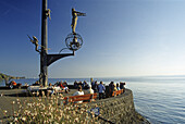 Skulptur und Menschen an der Uferpromenade im Sonnenlicht, Meersburg, Bodensee, Baden-Württemberg, Deutschland