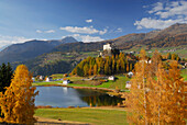 Lake with trees in autumn colours and castle of Tarasp, Tarasp, Unterengadin, Engadin, Grisons, Switzerland