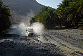 An all-terrain vehicle driving through a riverbed, Al Hajar mountains, Wadi Bani Auf, Oman, Asia