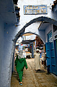 People in a narrow alley of Chefchaouen's medina, Chefchaouen, Morocco, Africa